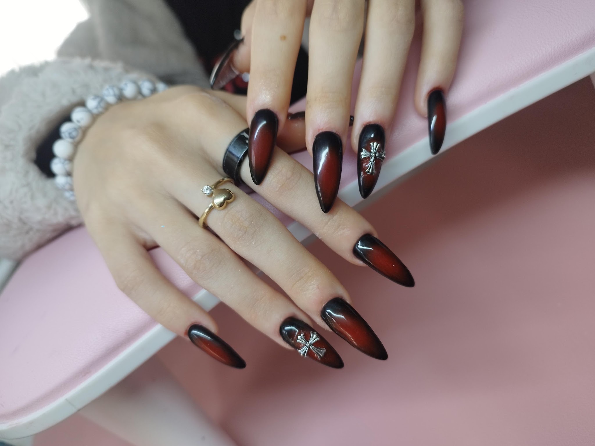 Lange zwart-rode stilettonagels met een bedeltje aan één nagel