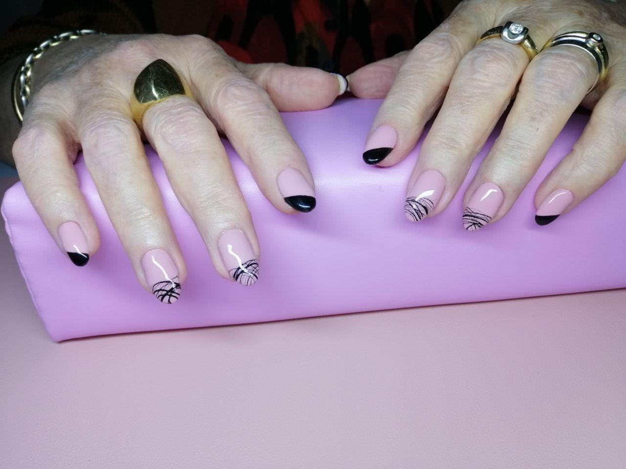 Nude nagels met zwarte tips en fijne zwarte lijntjes op een paarse handsteun